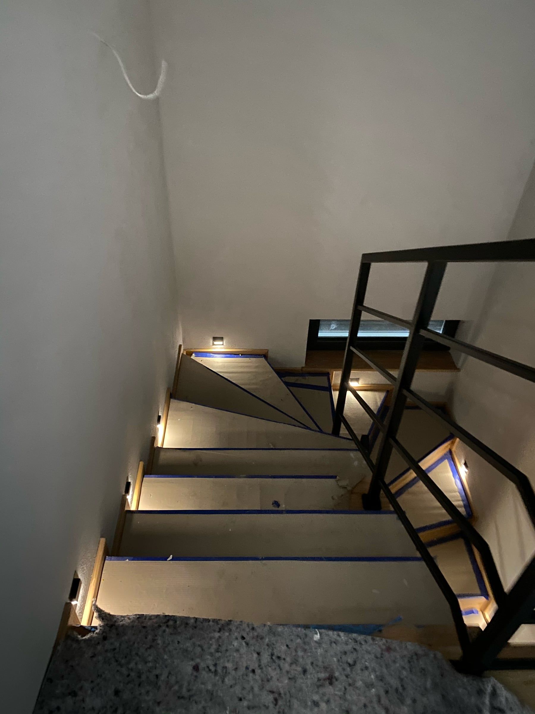 Schody z oprawami w ścianie przy stopniach i stalową balustradą, widok z góry
